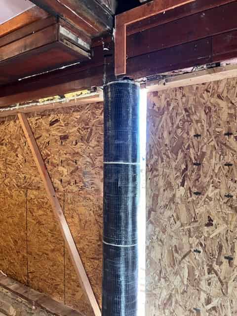 Carbon fiber fabric bonded to a structural beam beneath a wood subfloor during a seismic FRP retrofit